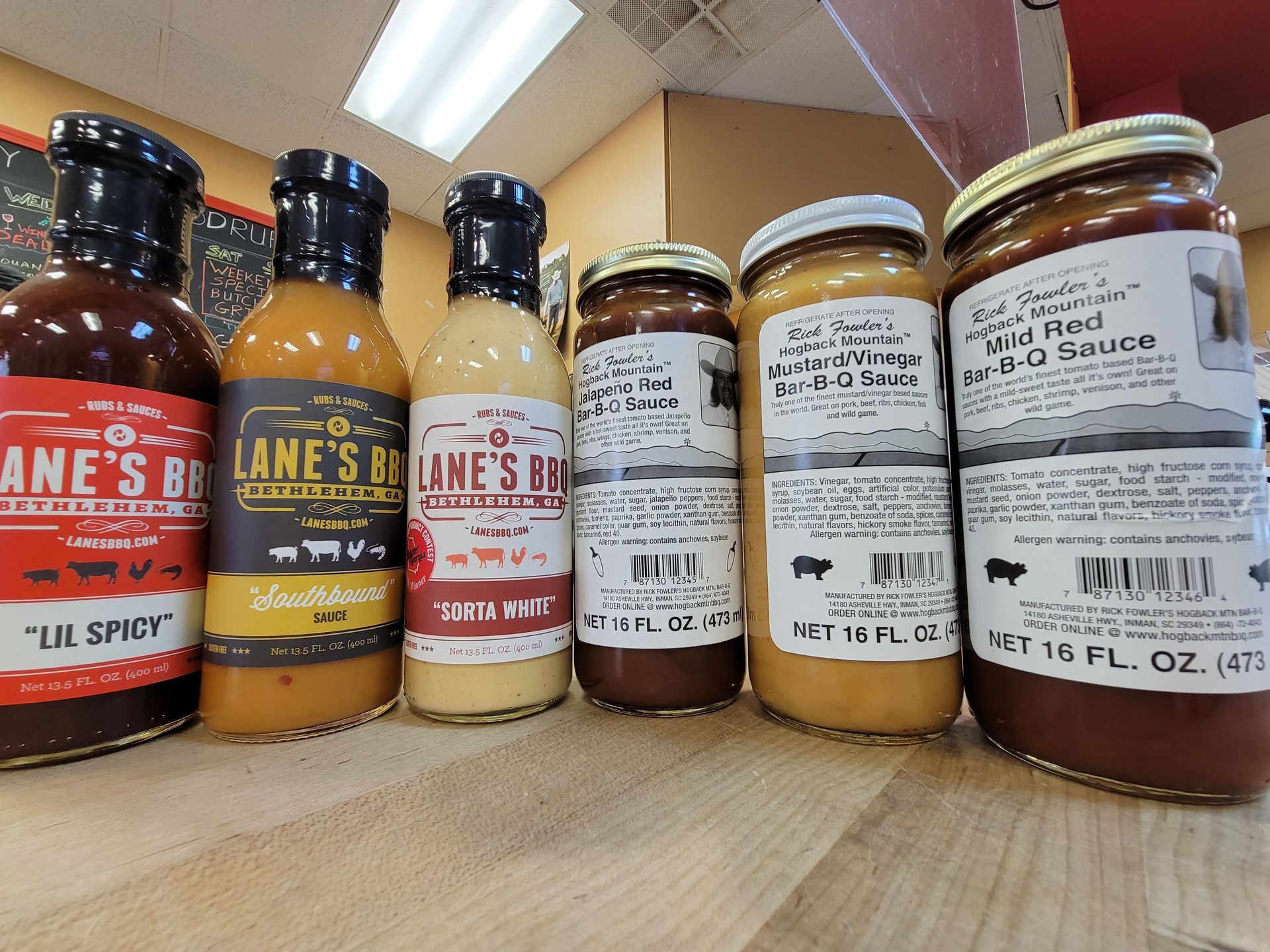 Bottles of barbecue sauce on a shelf, various brands and flavors.