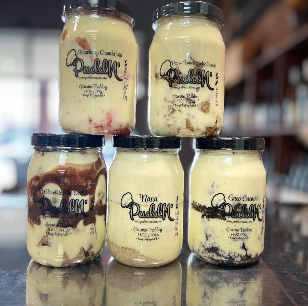 Five jars of layered dessert with various toppings on a counter.