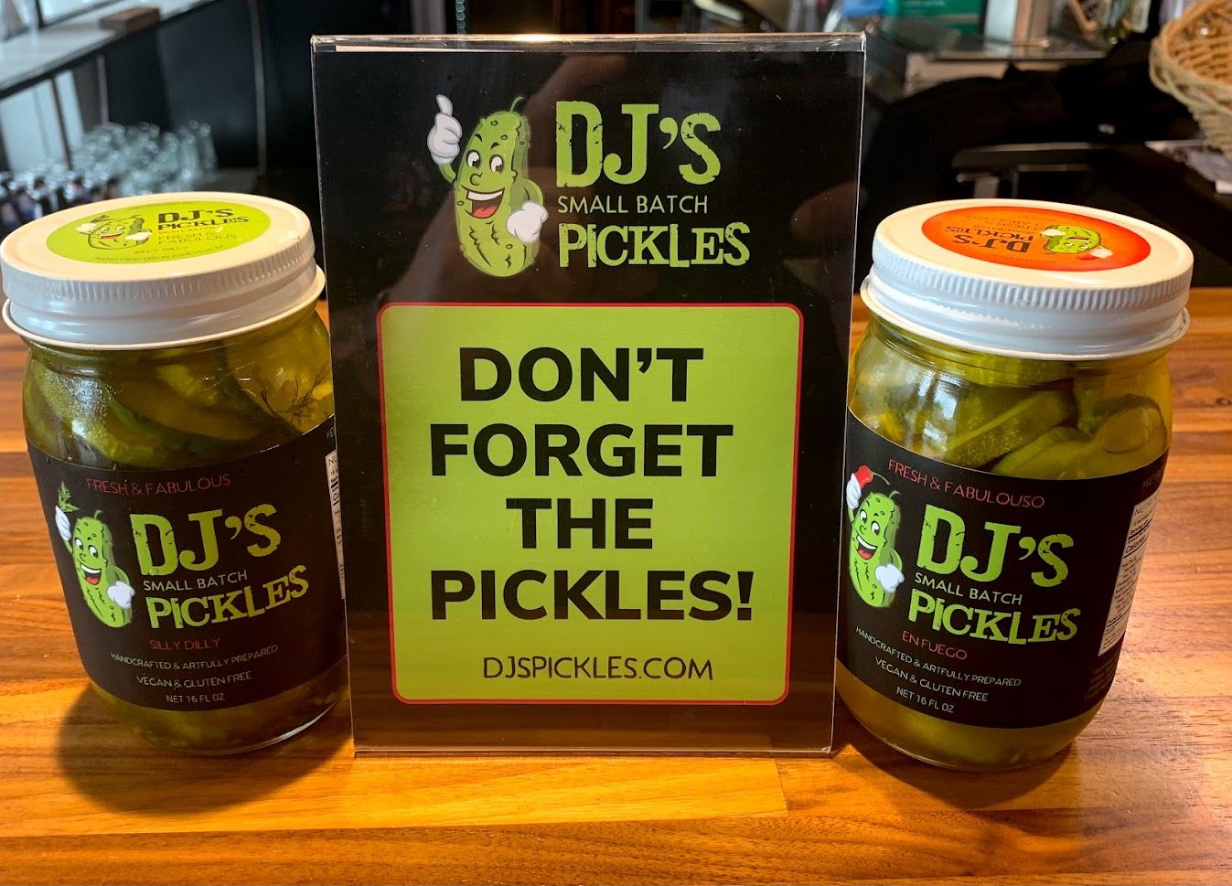Two jars of DJ's brand pickles with a sign that reads