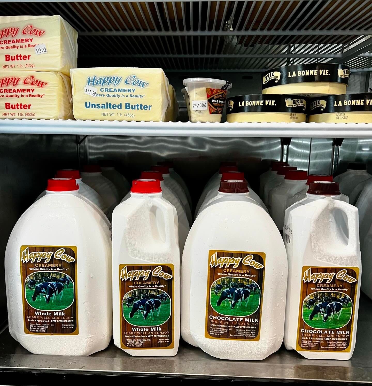 Refrigerated dairy case: milk jugs, butter packages, and cheese wheels.