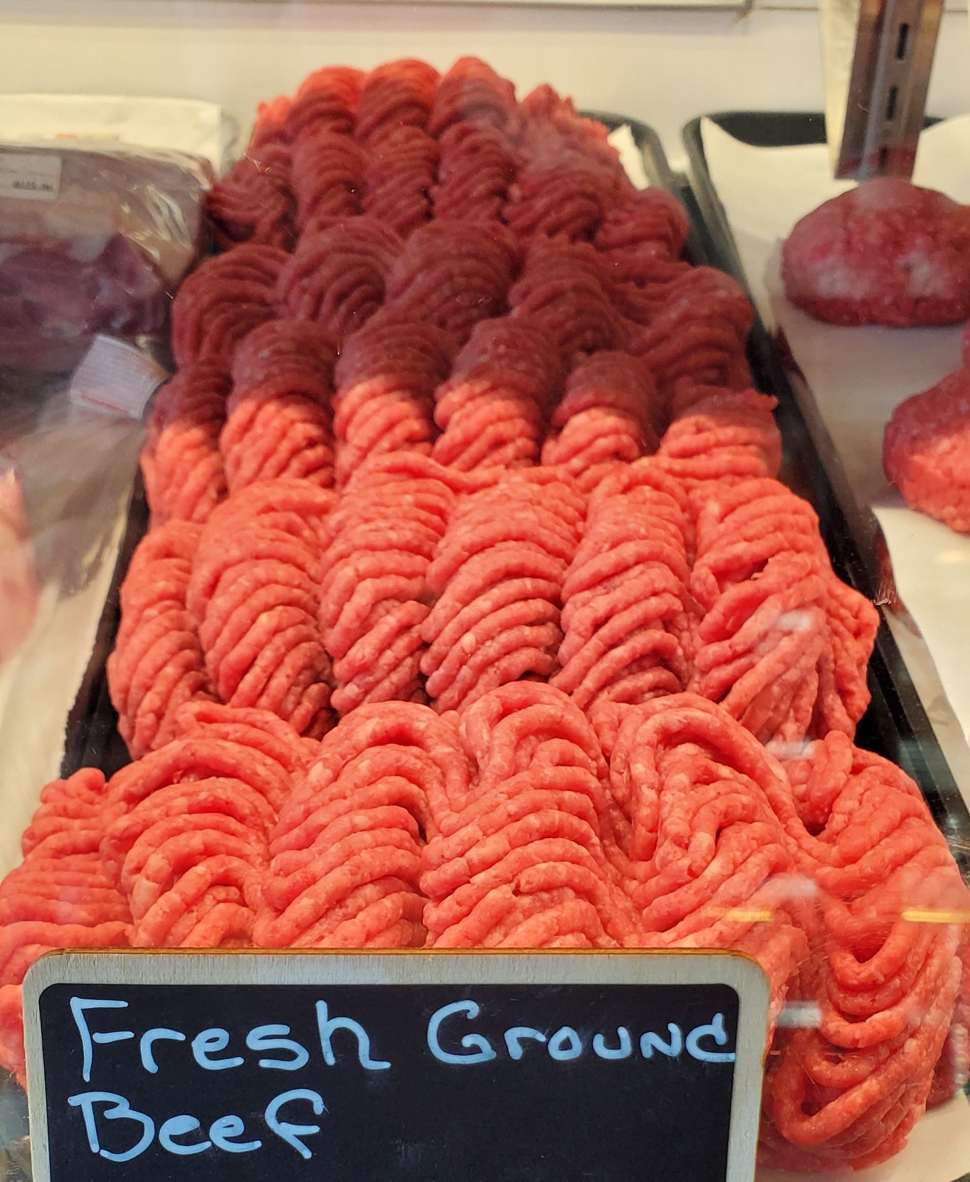 Fresh ground beef displayed in a butcher shop, arranged with a color gradient from light to dark red.