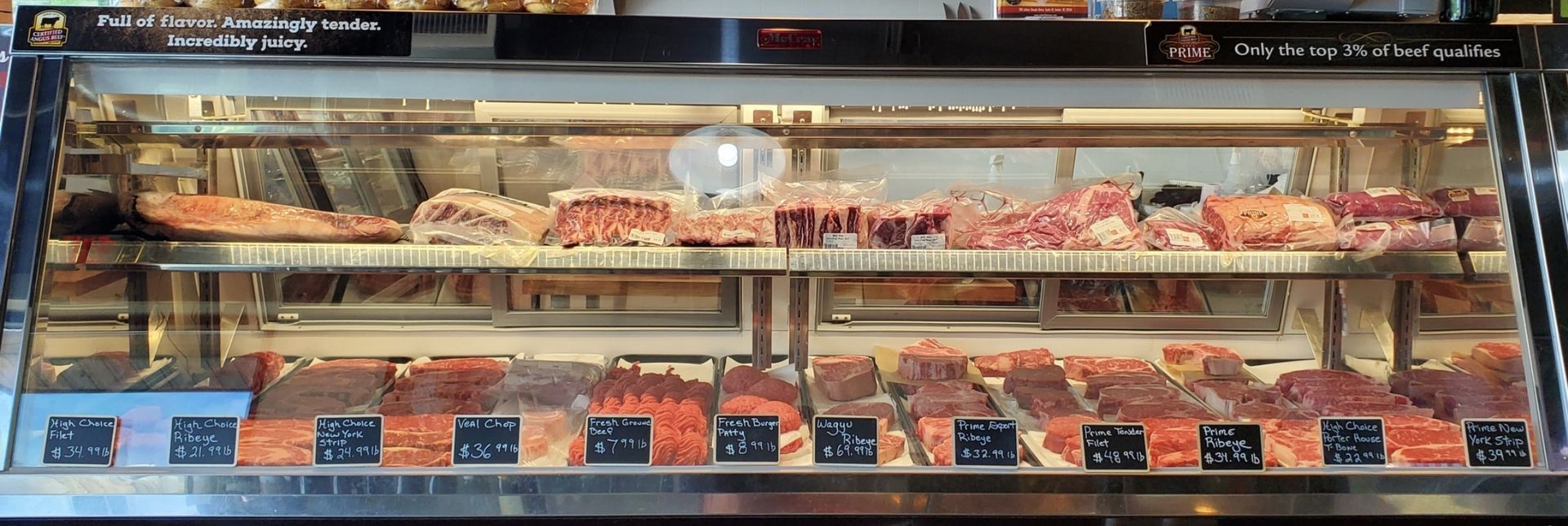 Meat display case with various cuts of red meat for sale.