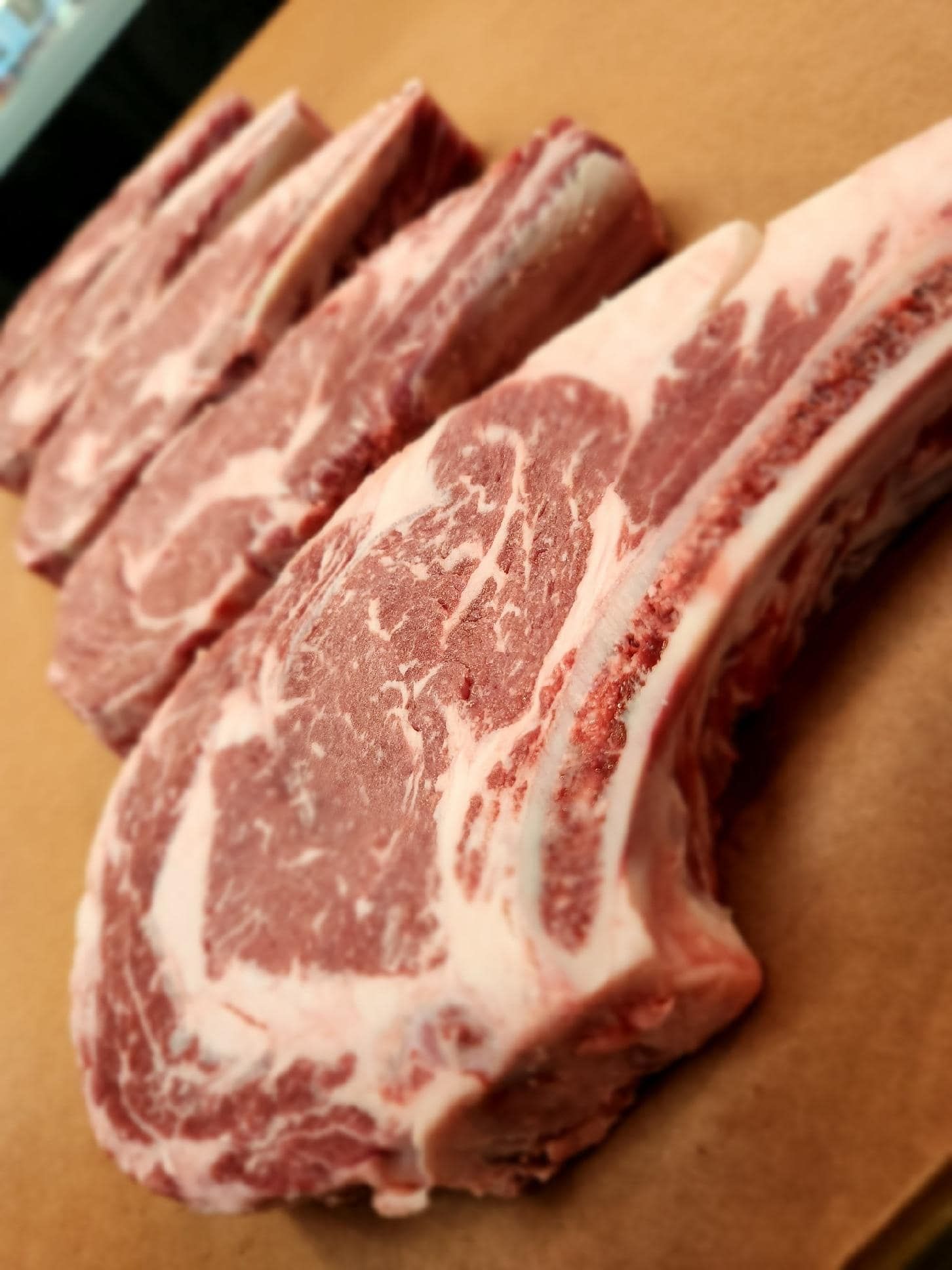 Raw lamb chops, showing marbled red meat and bone, arranged on a surface.