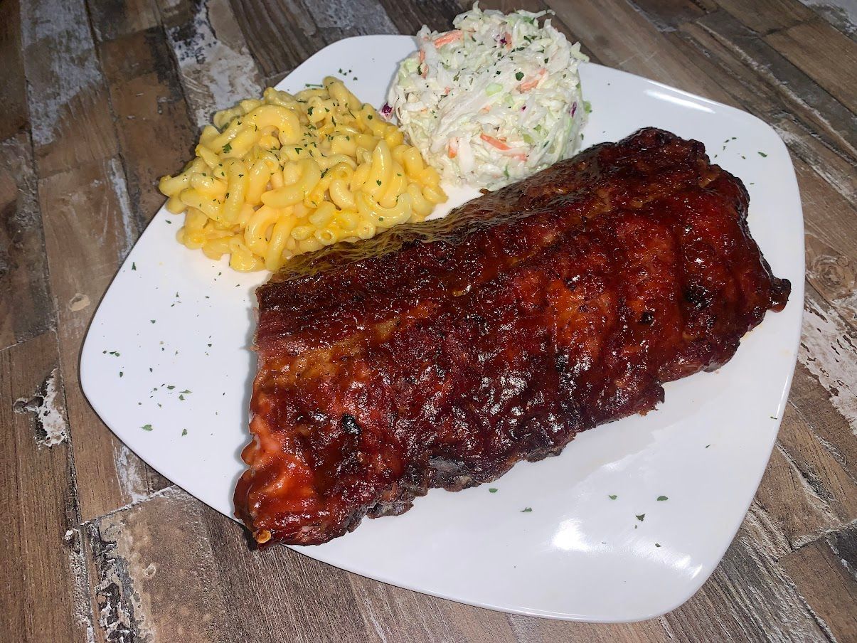 Plate of ribs with mac and cheese and coleslaw.