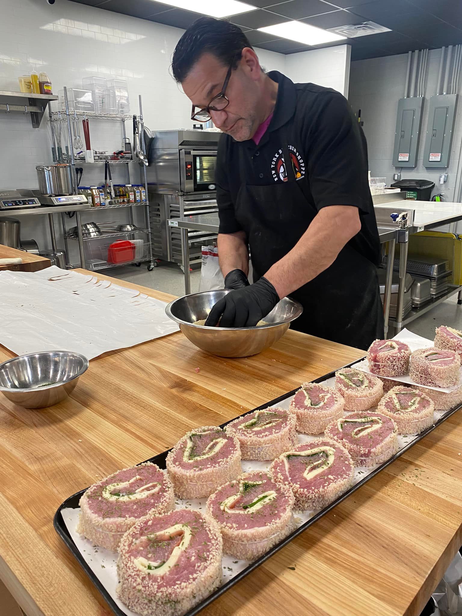 Chef preparing food in a kitchen; rolling meat rolls.