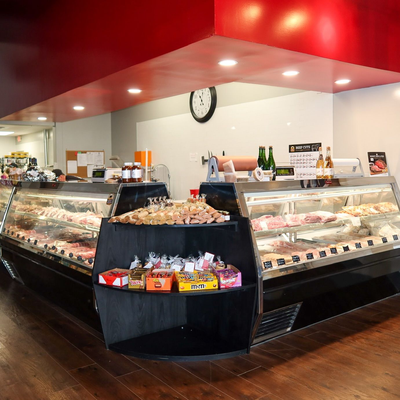 Butcher shop with meat displays, red ceiling, and black shelves.