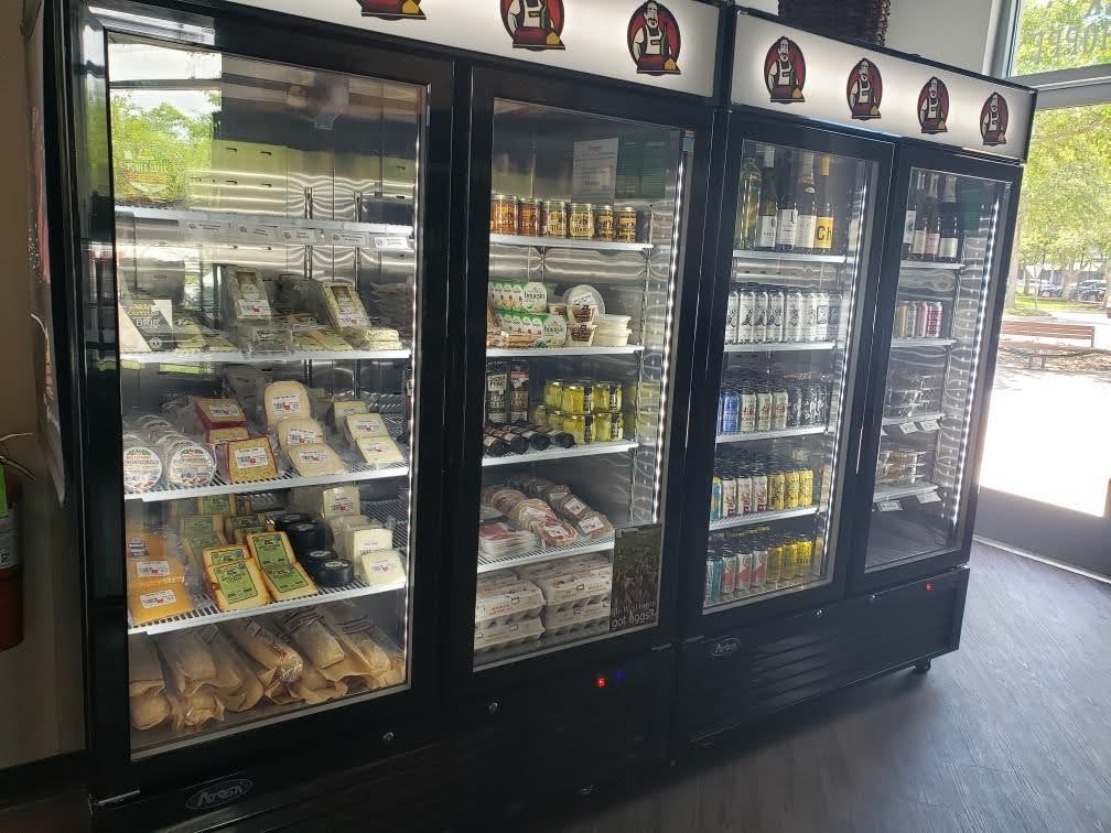 Refrigerated display cases filled with cheeses, eggs, and other goods at a store.