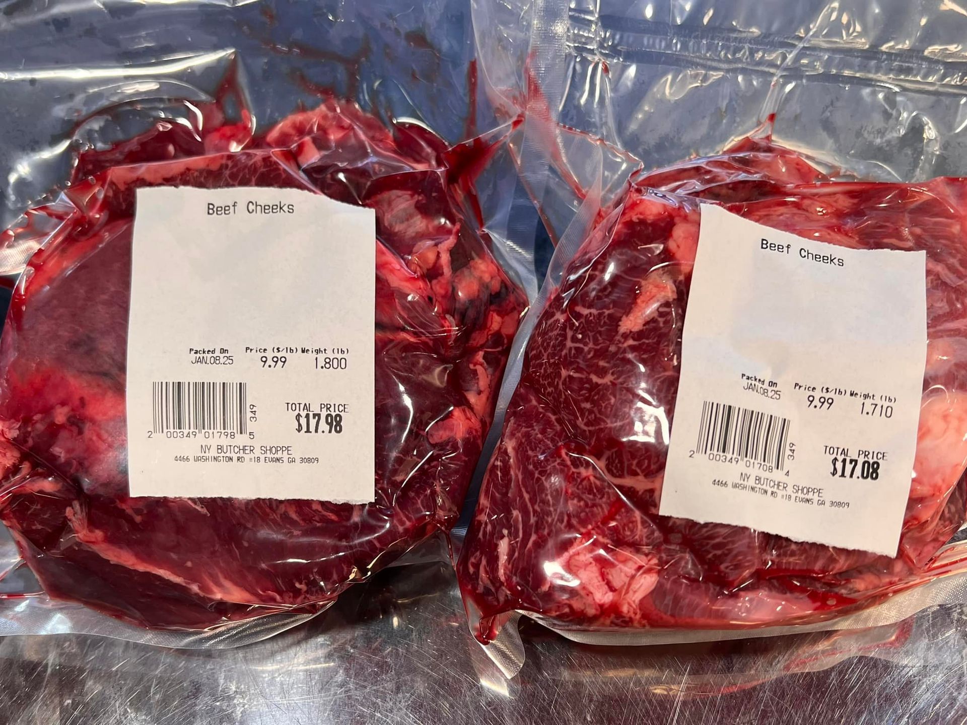 Two vacuum-sealed packages of raw beef with labels, resting on a silver surface.