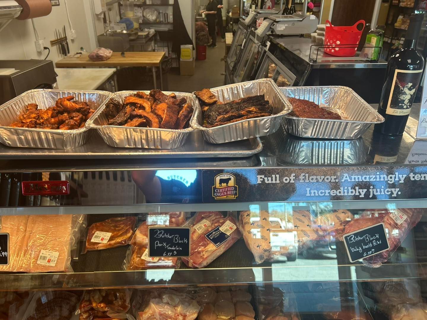 Display case with prepared barbecue meats above refrigerated deli meats.