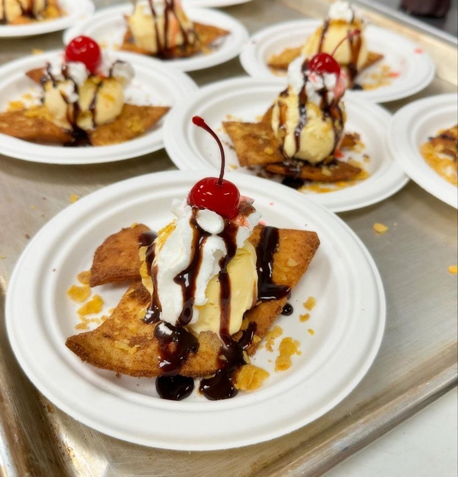 Plated fried dough with ice cream, whipped cream, chocolate sauce, and a cherry.