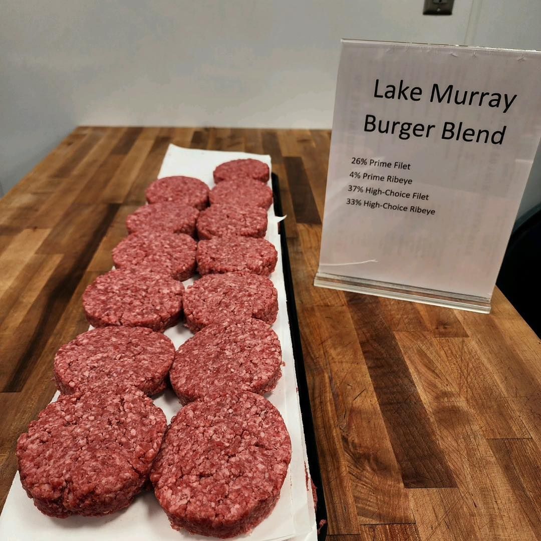 Raw burger patties on a tray next to a sign labeled
