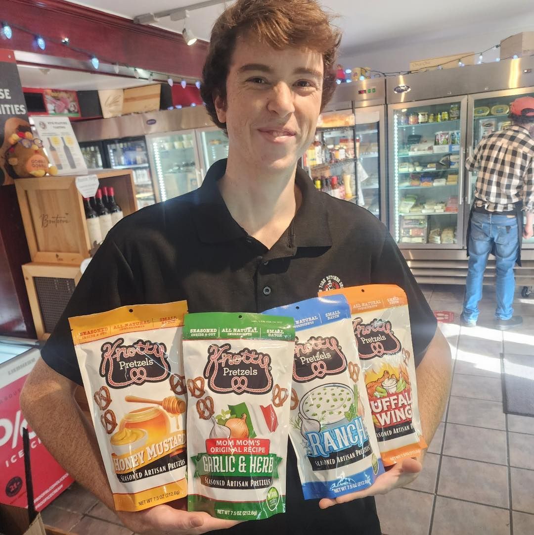 Man holding four bags of flavored pretzels in a store.