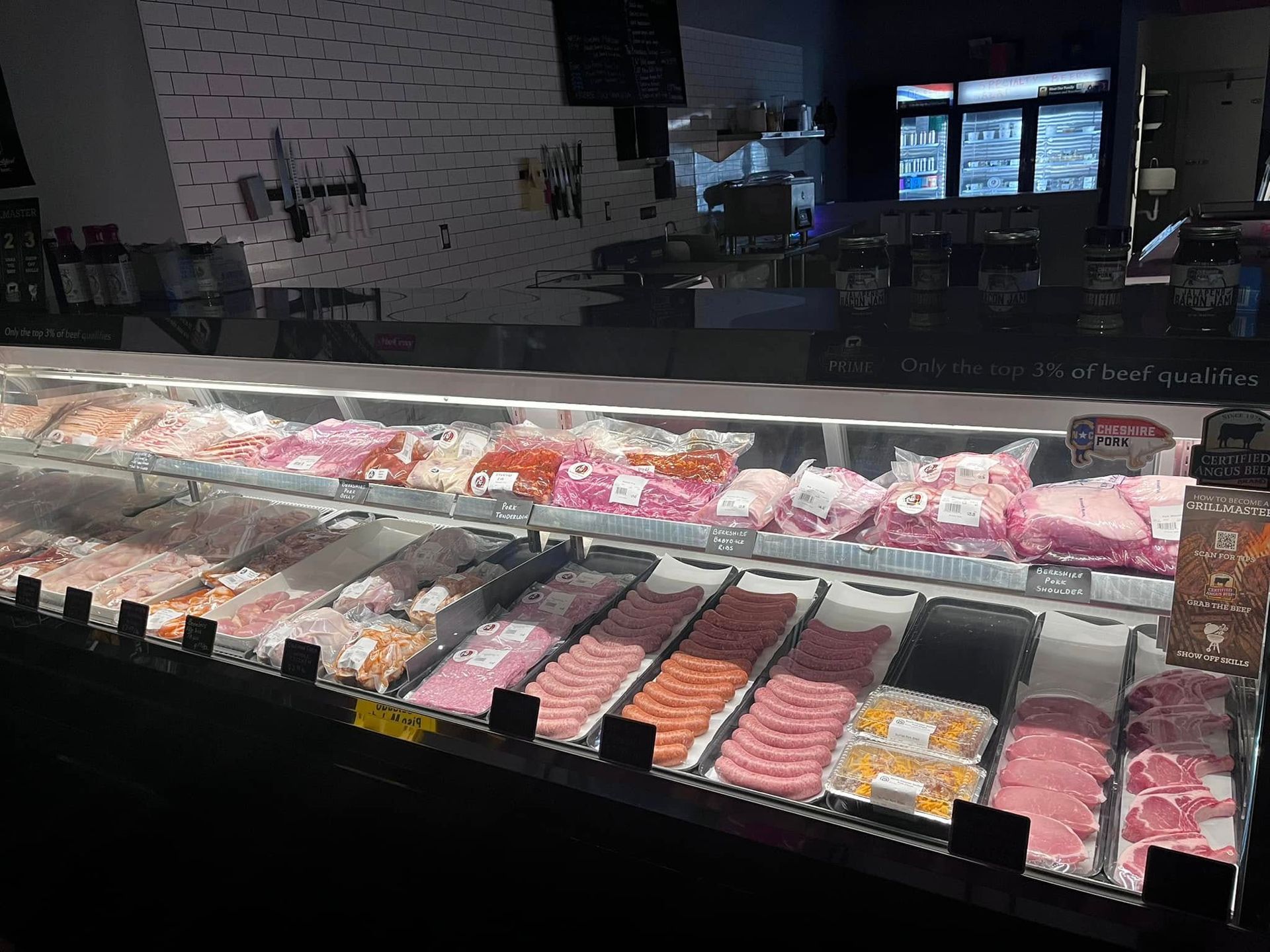 Meat display case in a store, filled with various cuts of raw meat, brightly lit.