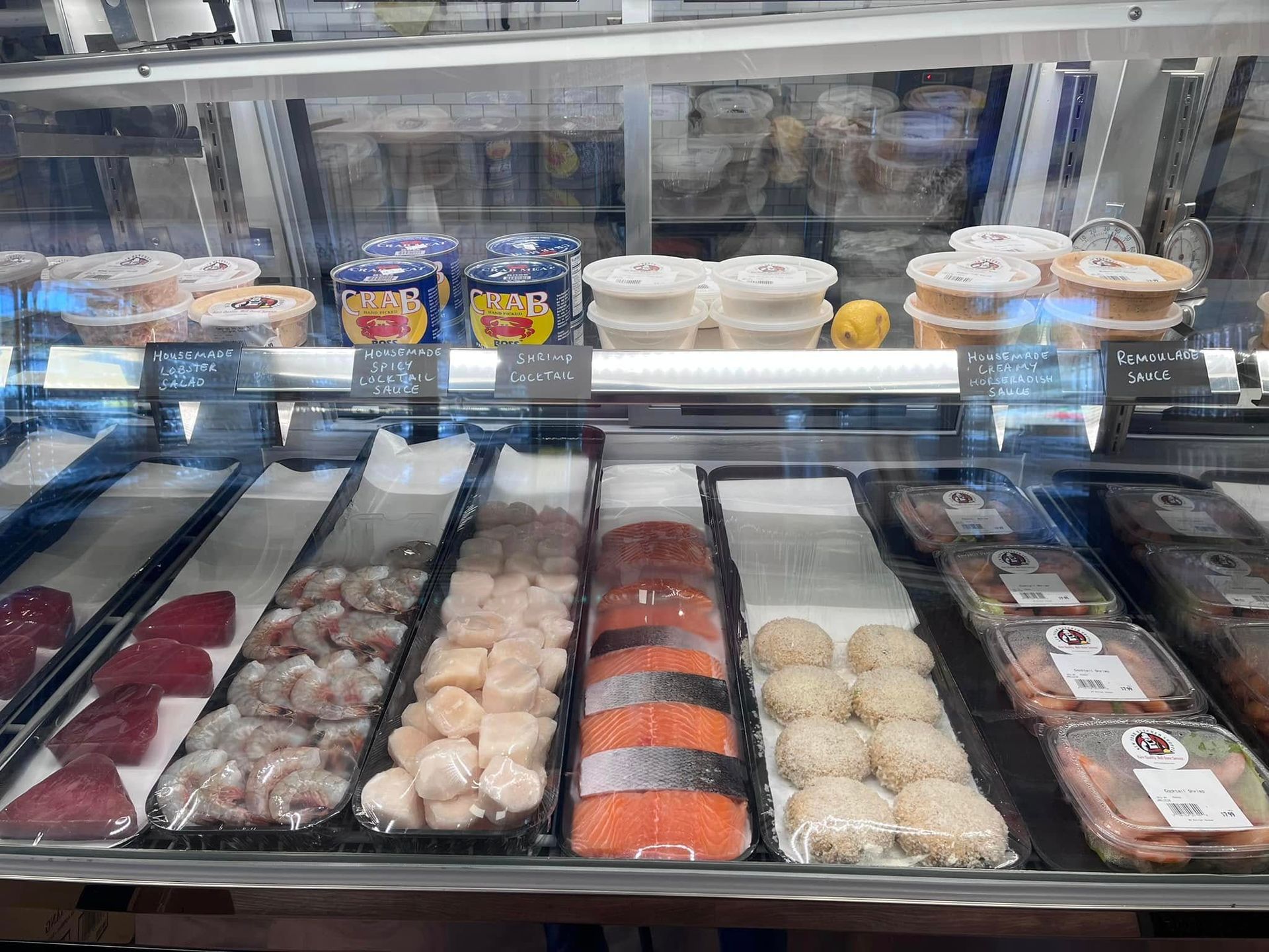 A refrigerated seafood display case with various packaged raw fish and prepared items.