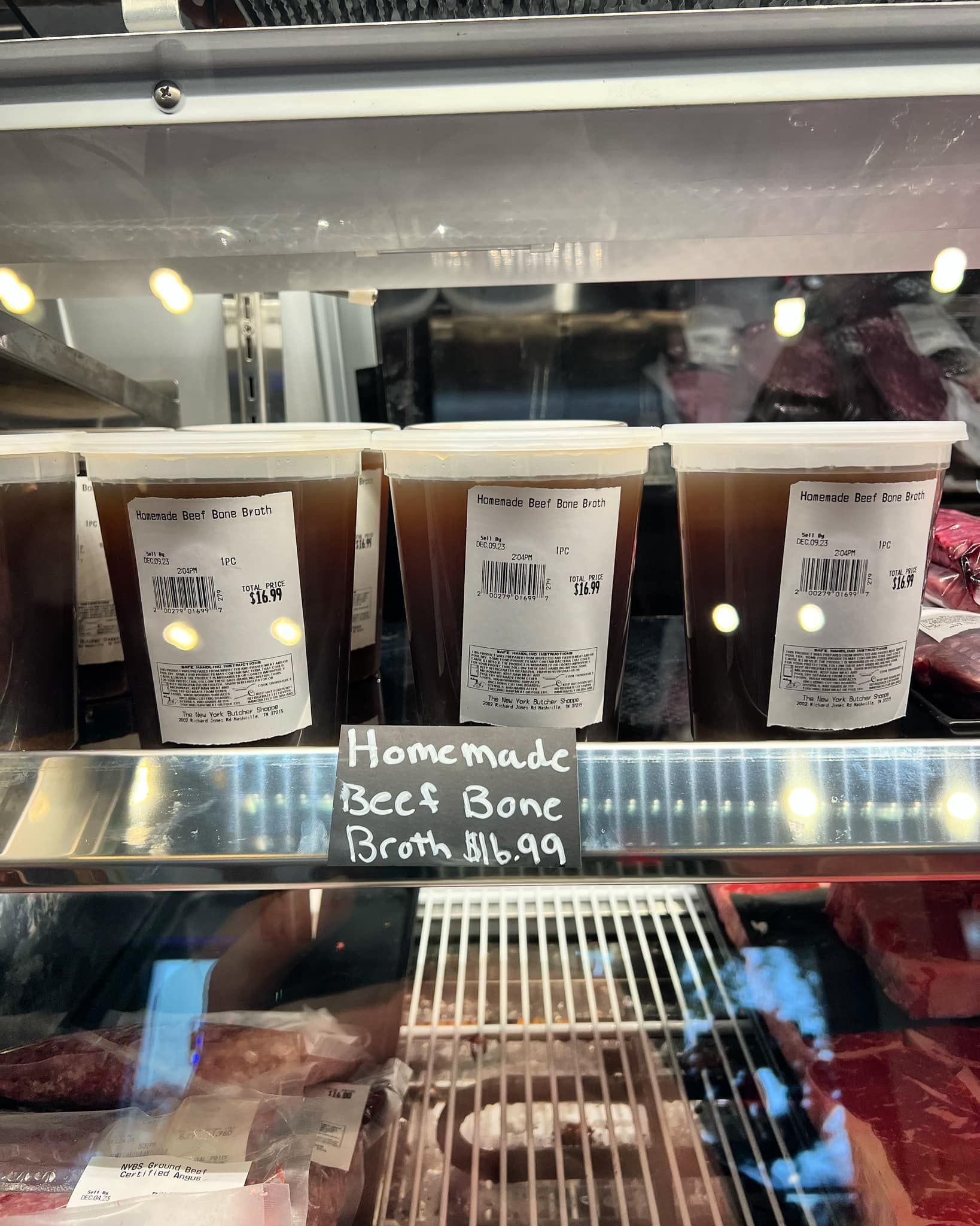 Display case with containers of homemade beef bone broth. Price tag says $16.99.