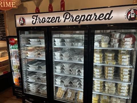 Refrigerated display case with pre-made frozen meals, labeled