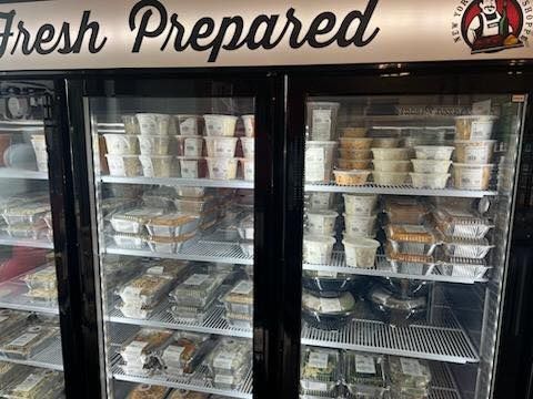 Refrigerated display case filled with prepared food containers labeled