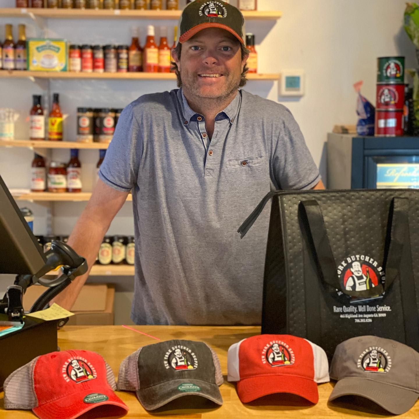 Man in a shop, wearing hat, smiling