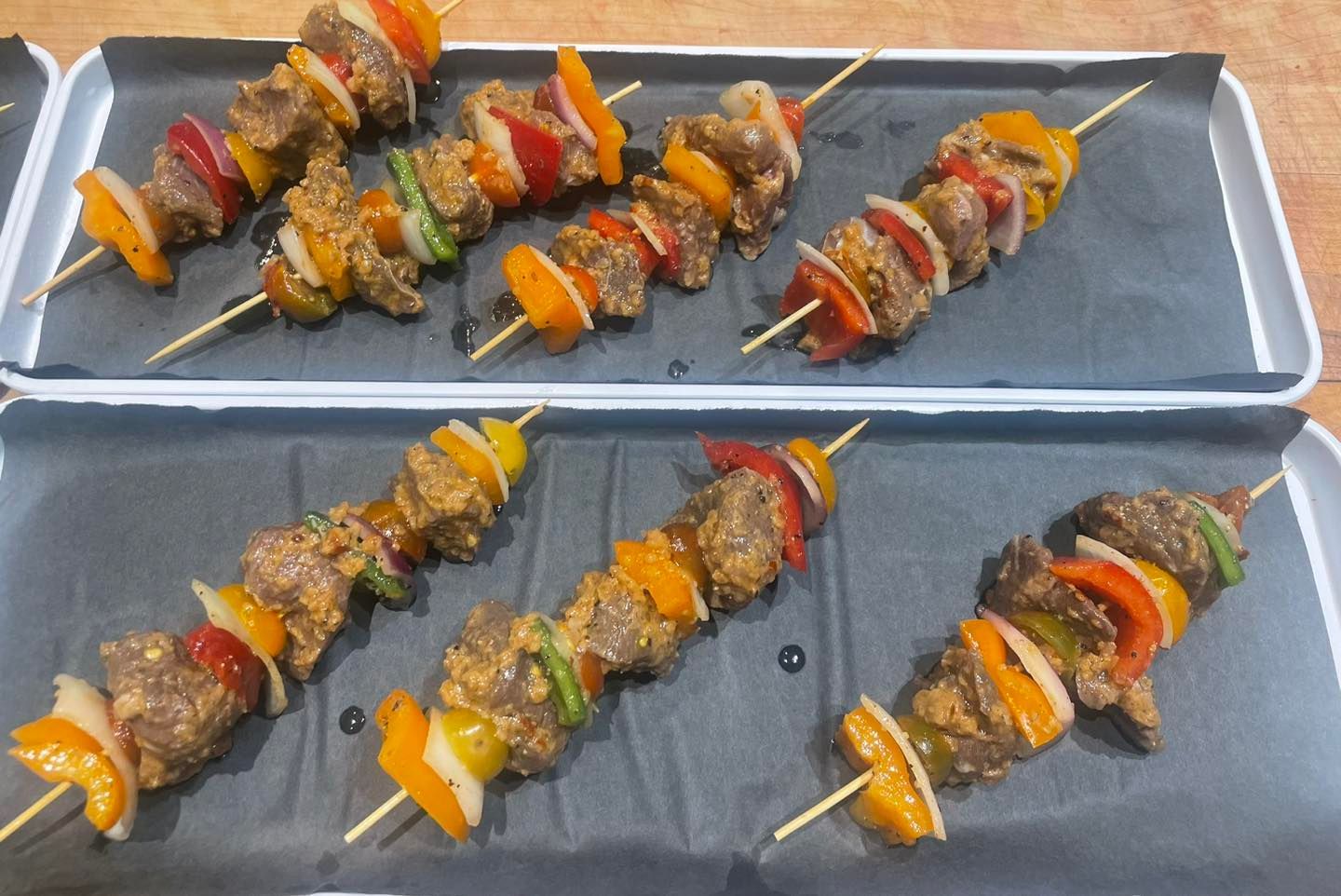 Skewers with marinated meat and colorful bell peppers arranged on trays