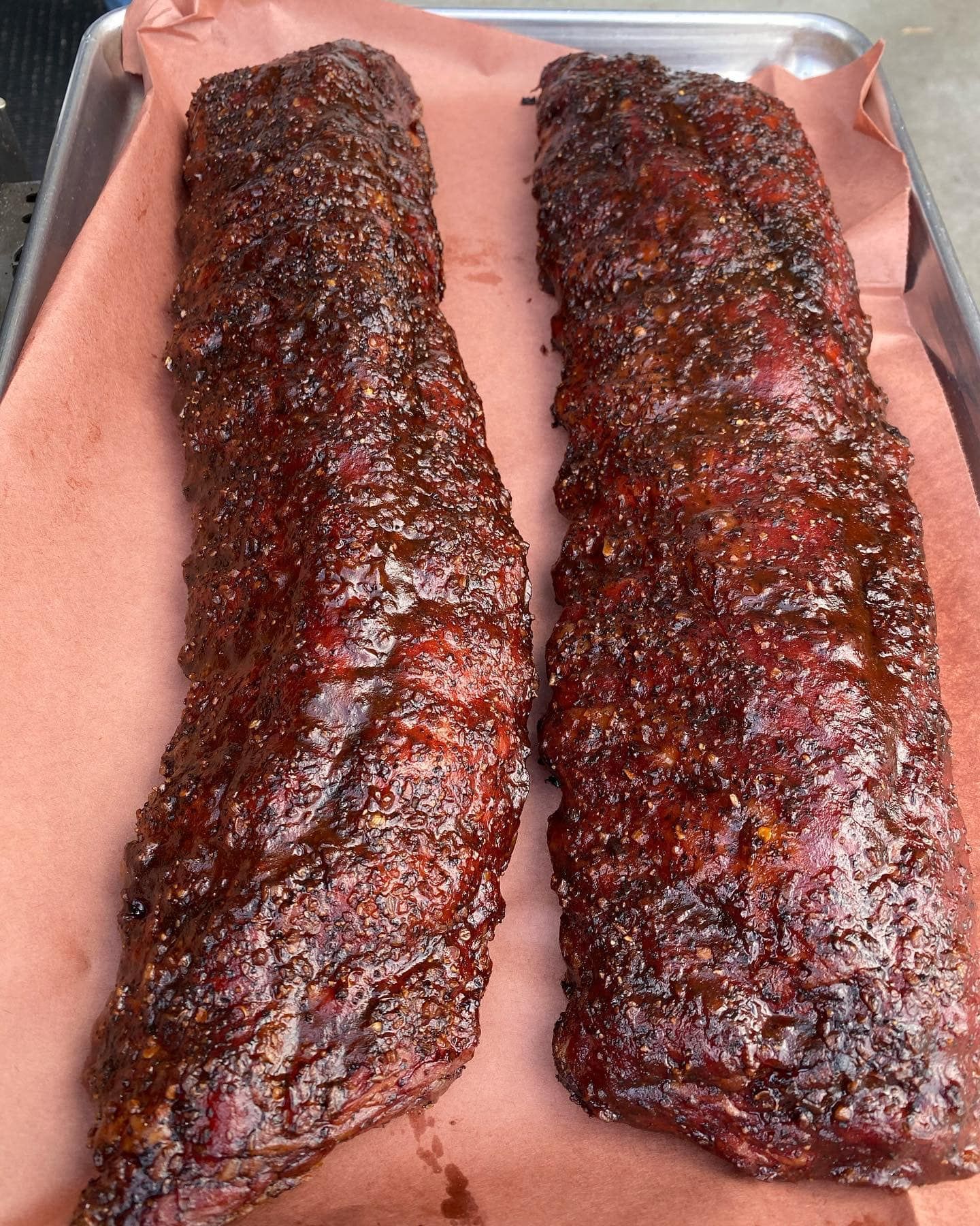 Two racks of smoked ribs on a tray