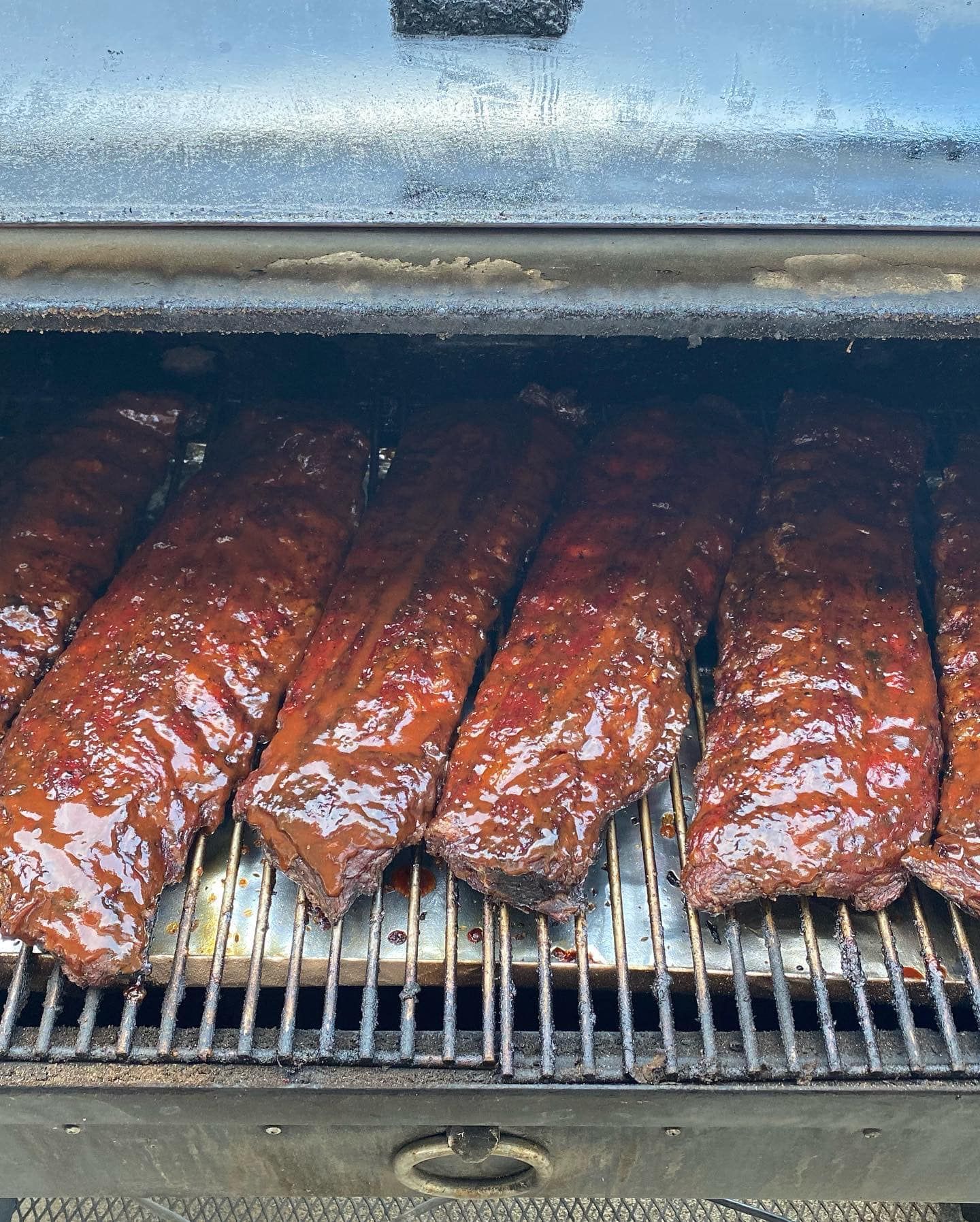 Smoked ribs on a grill, glistening with barbecue sauce
