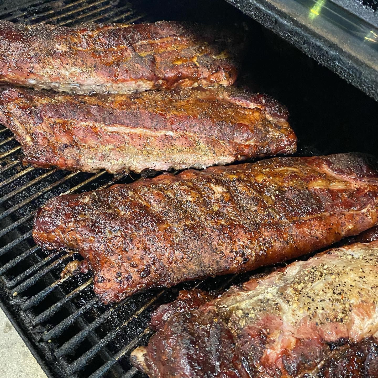 Rack of seasoned ribs grilling on a BBQ pit