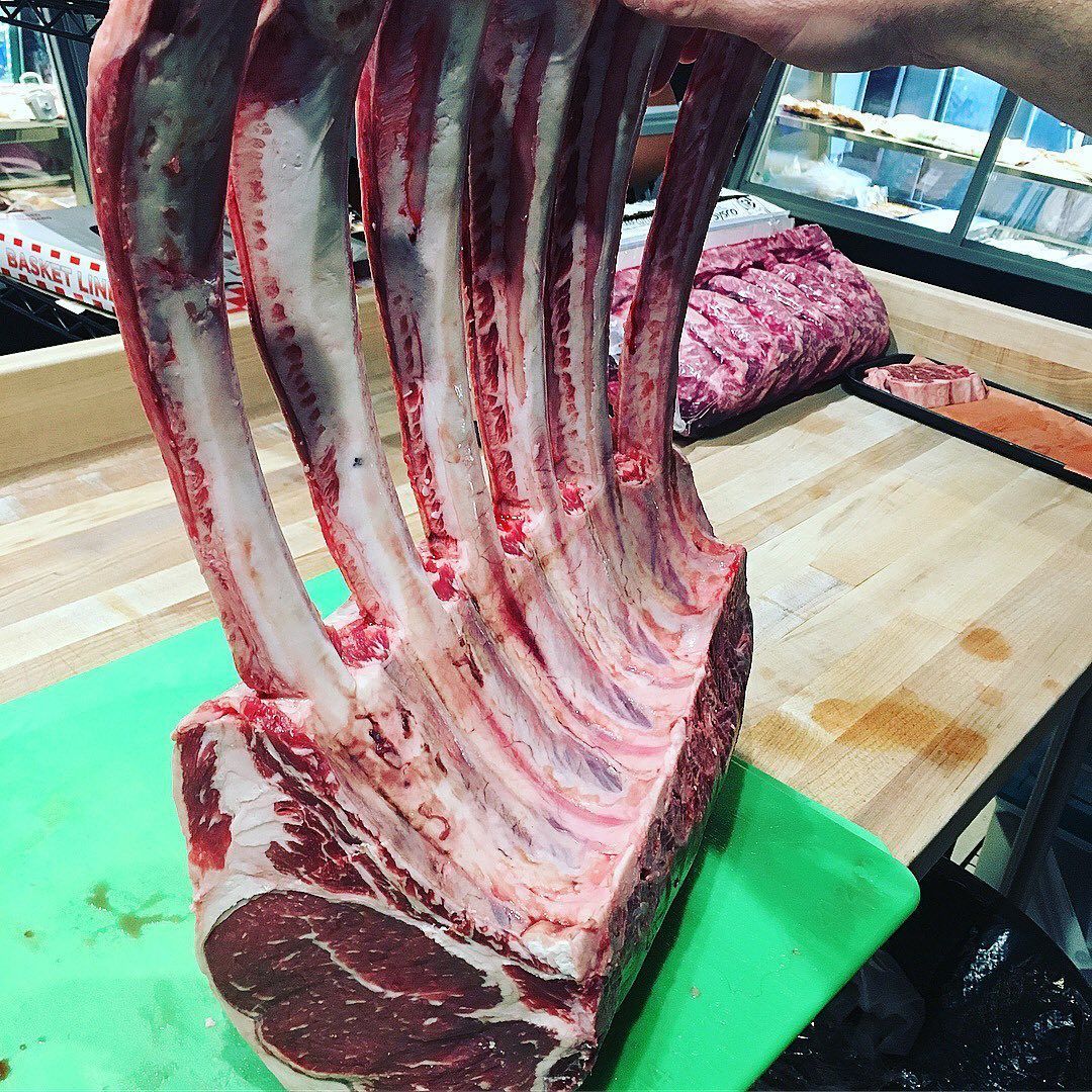A raw, thick-cut, bone-in rib