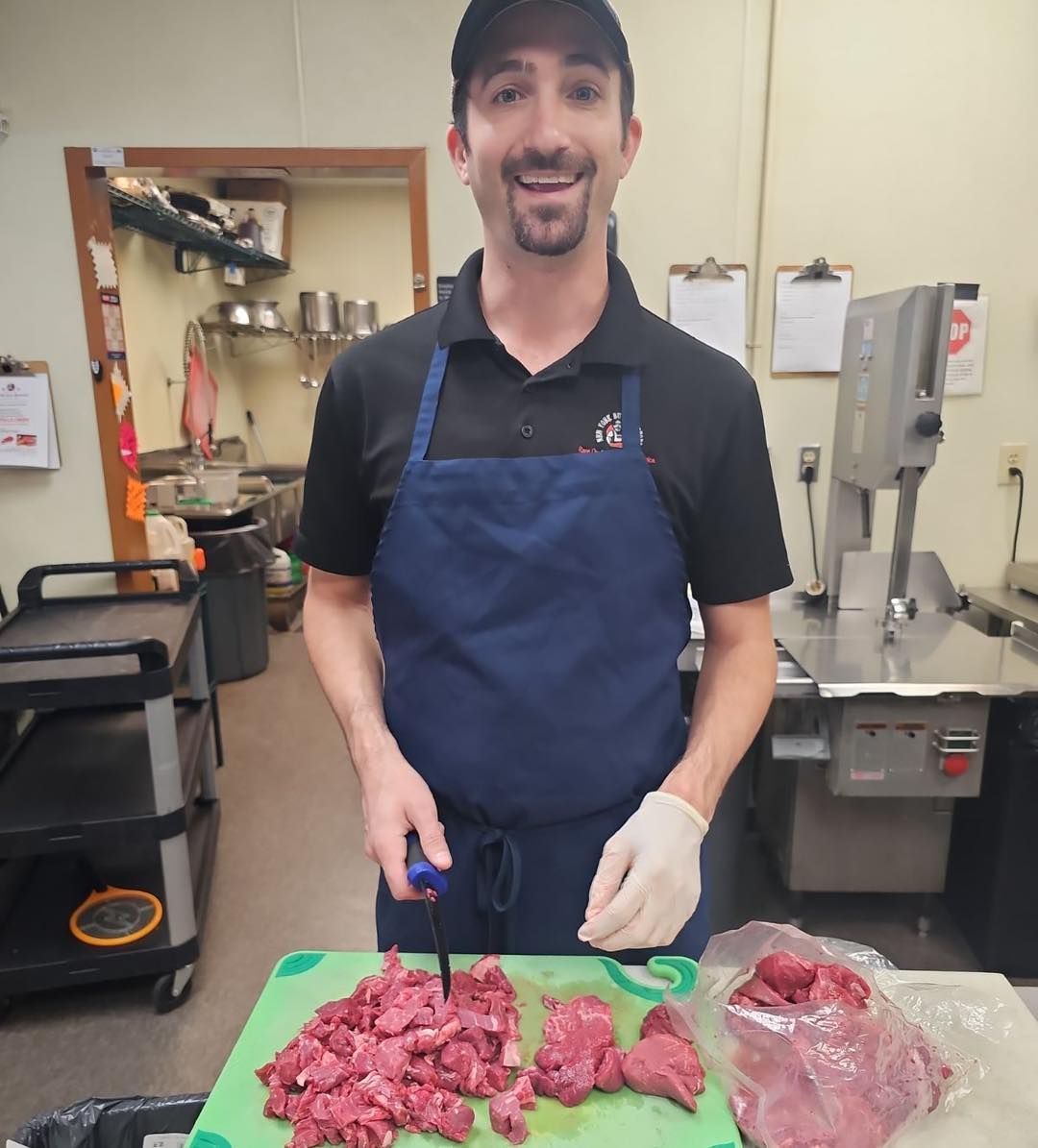 Man in apron smiles while chopping meat
