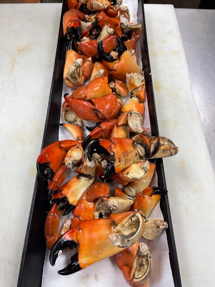 Pile of cooked stone crab claws on a rectangular black tray