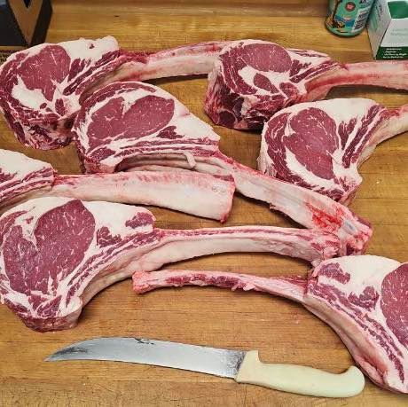 Tomahawk steaks on a wooden surface with a knife