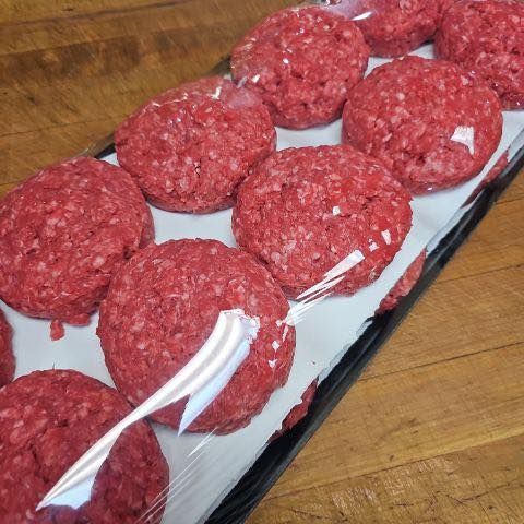Raw hamburger patties arranged in a tray