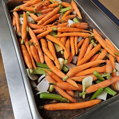 Tray of roasted carrots, celery, and onions, seasoned with pepper