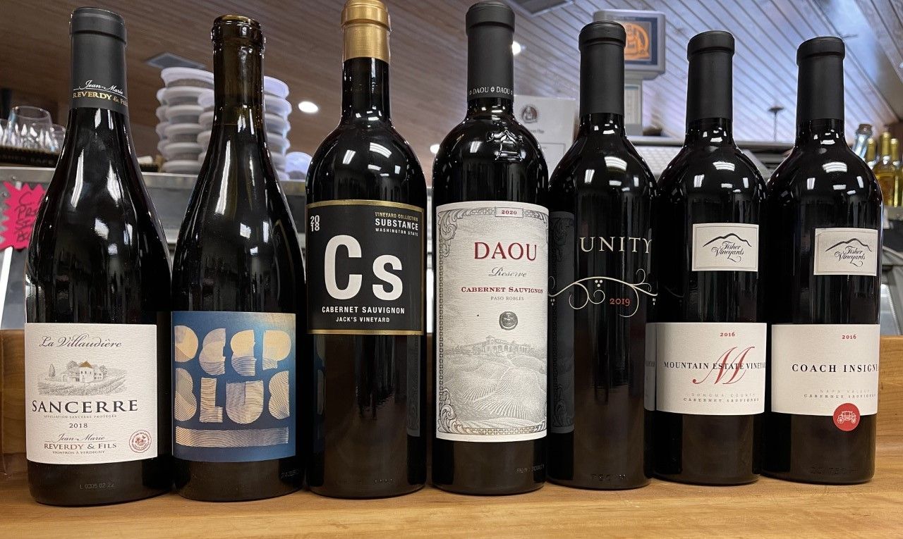 Seven wine bottles on a table with varying label designs and colors
