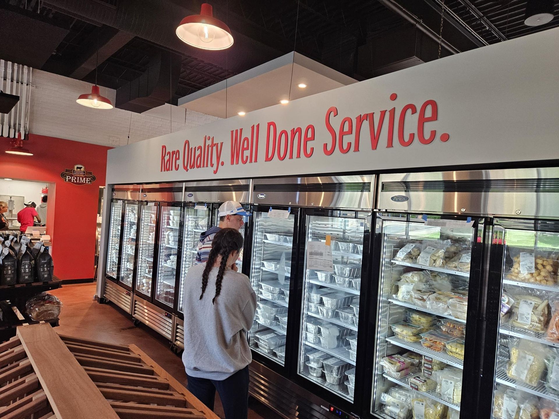 Customers browsing refrigerated food display in a store