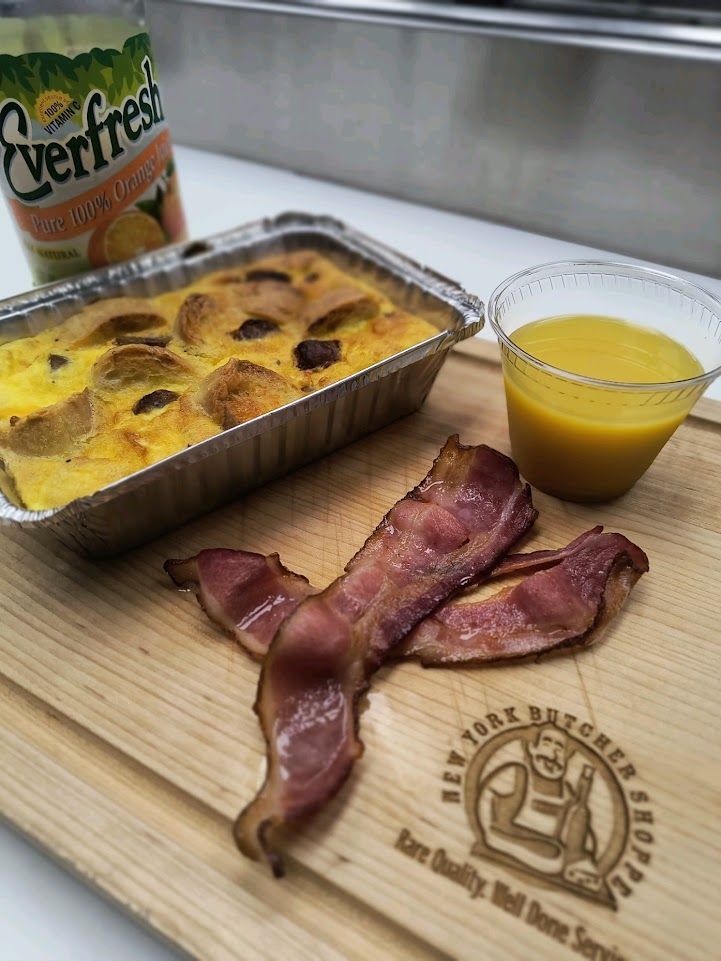 Breakfast: Bacon, casserole, juice, and orange juice on a cutting board with a can of orange juice in the background.