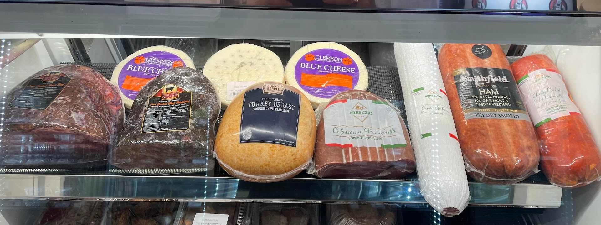 A display case filled with various cheeses and sausages in a refrigerated section of a store.