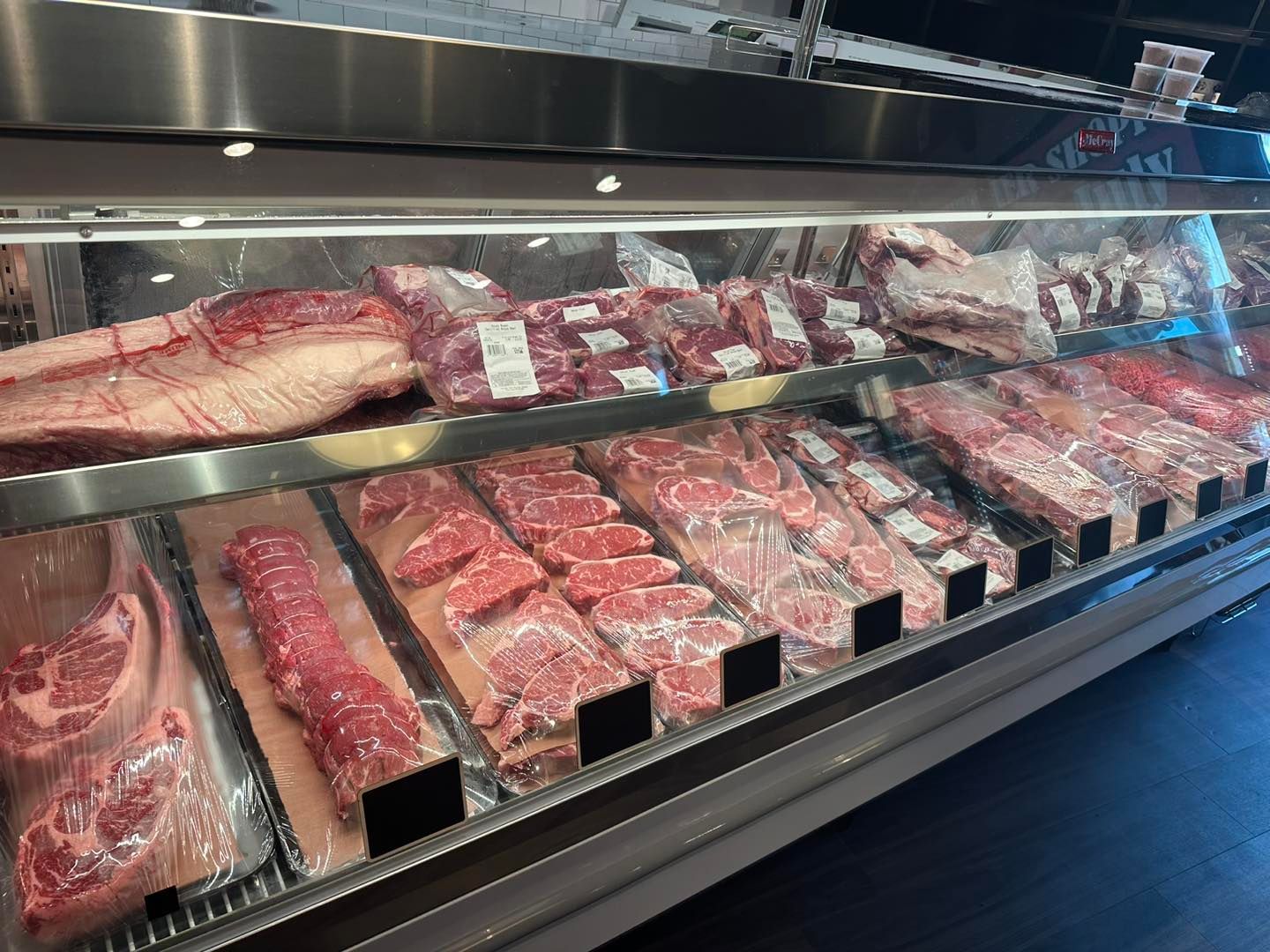 Meat display case at a butcher shop, showcasing various cuts of raw meat.