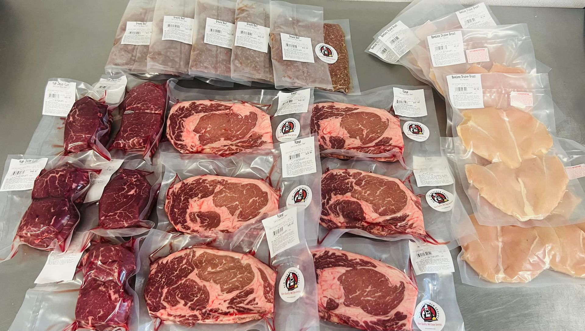 Assortment of vacuum-sealed raw meats: steaks, chicken breasts, ground meat, packaged on a counter.