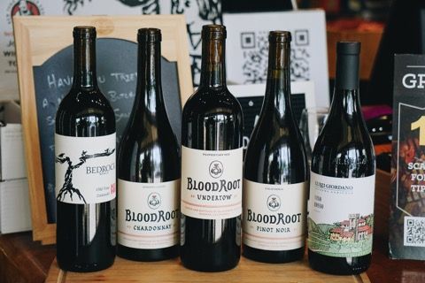 Five wine bottles lined up on a wooden surface; labels say