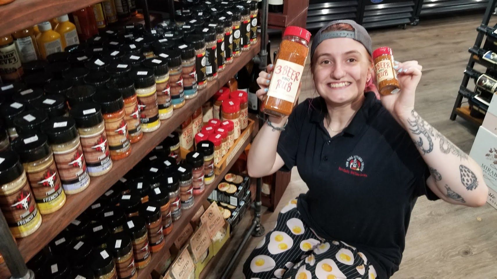 Woman in a shop holds spice jars. Shelves filled with spice jars. She smiles.