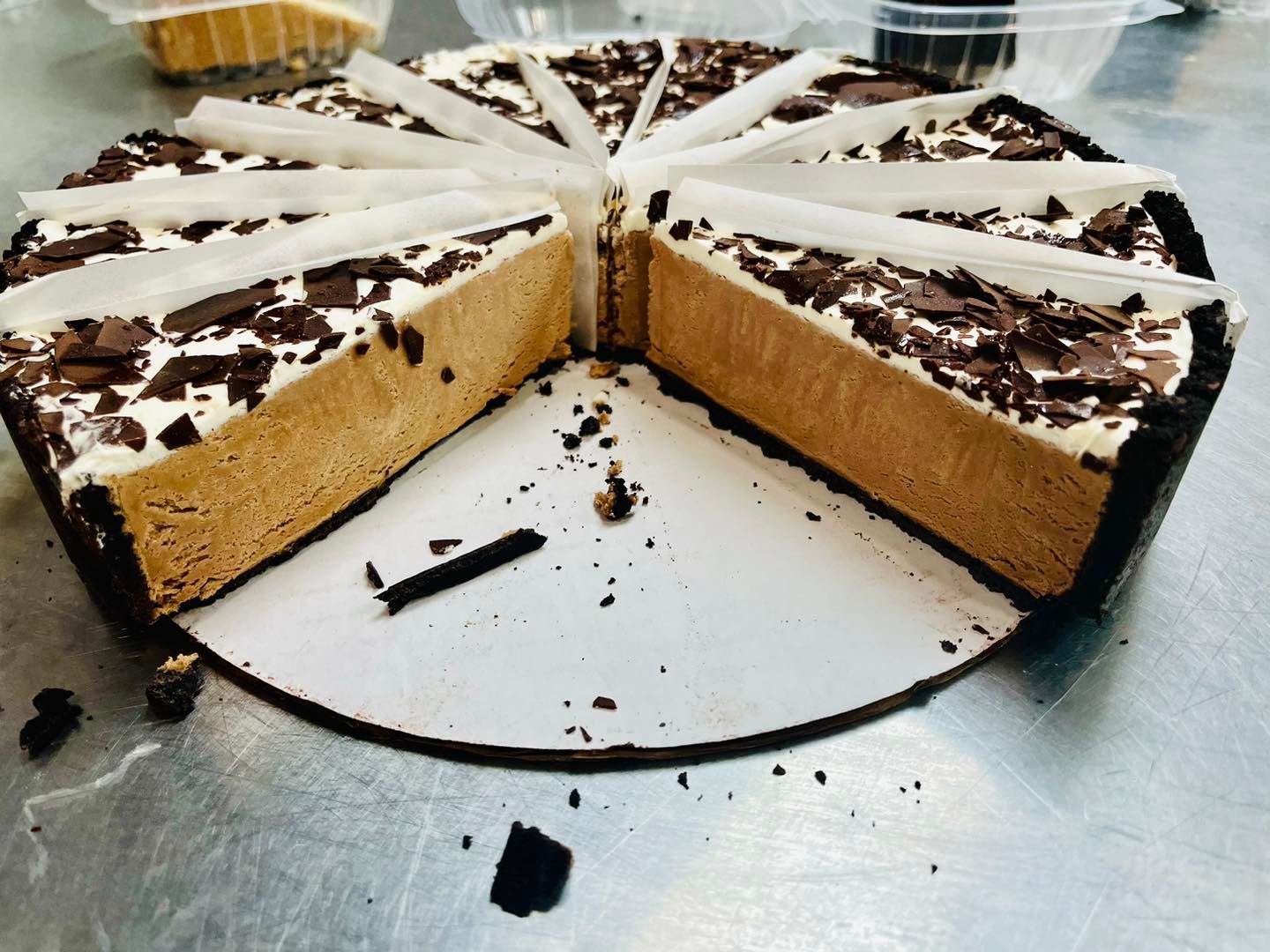 Chocolate mousse pie with shaved chocolate topping, sliced on a white serving board.