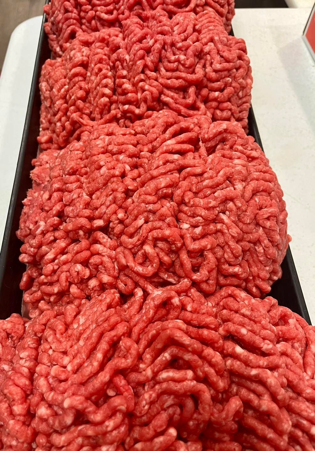 Ground beef in black trays, ready for sale.