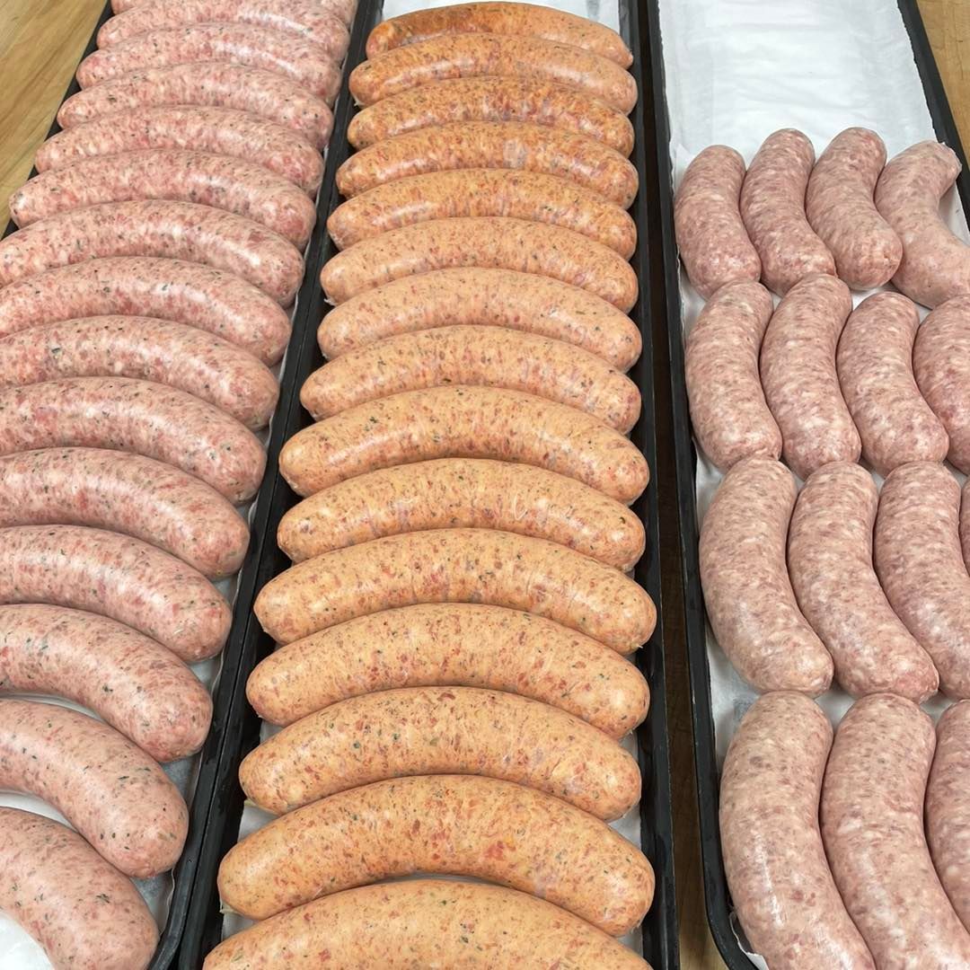 Rows of various sausages displayed on black trays.