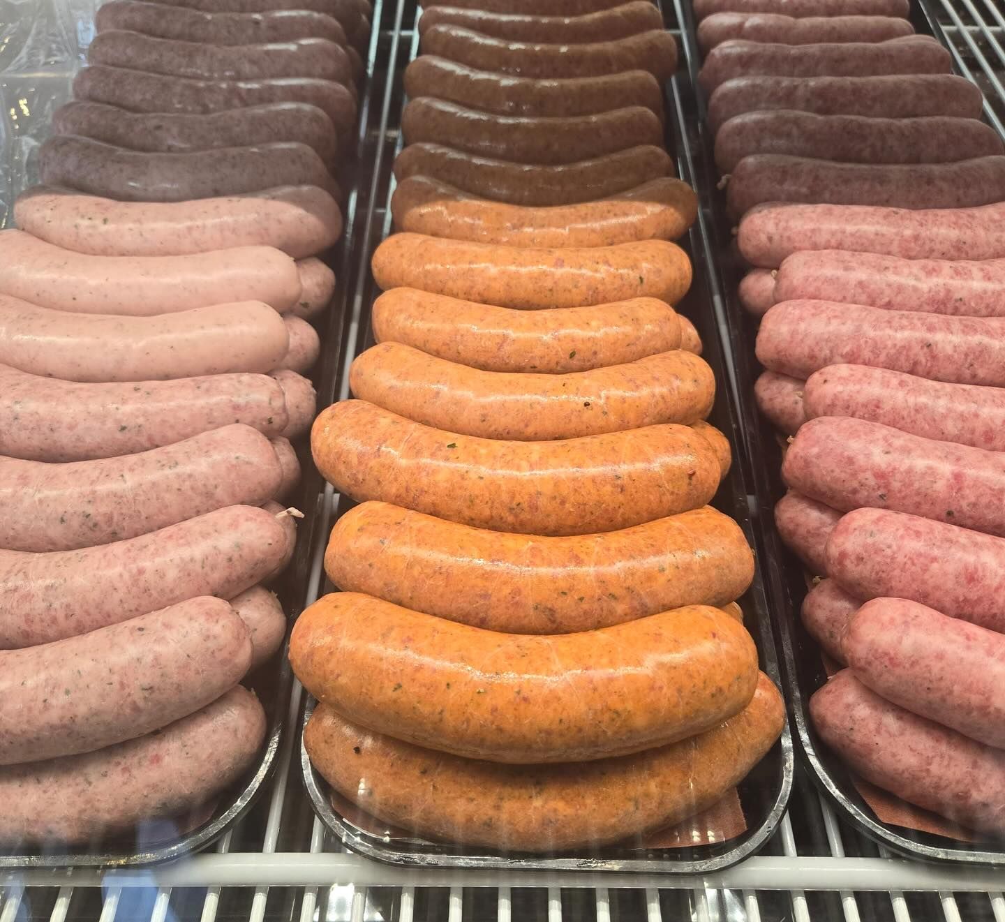 Rows of various sausages in a display case: dark brown, orange, and pink.