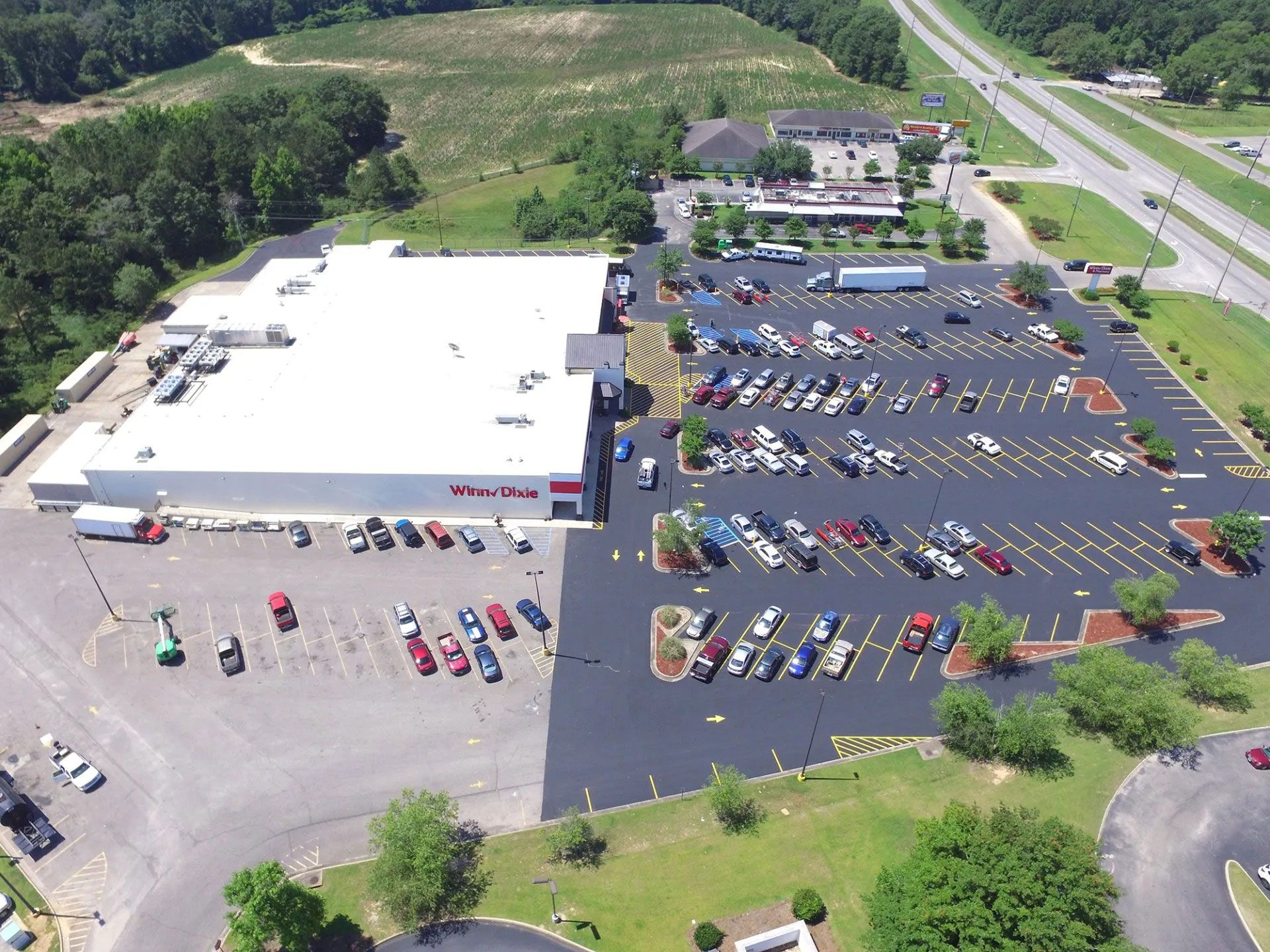 Aerial view of a large store with a full parking lot and surrounding roads and greenery.