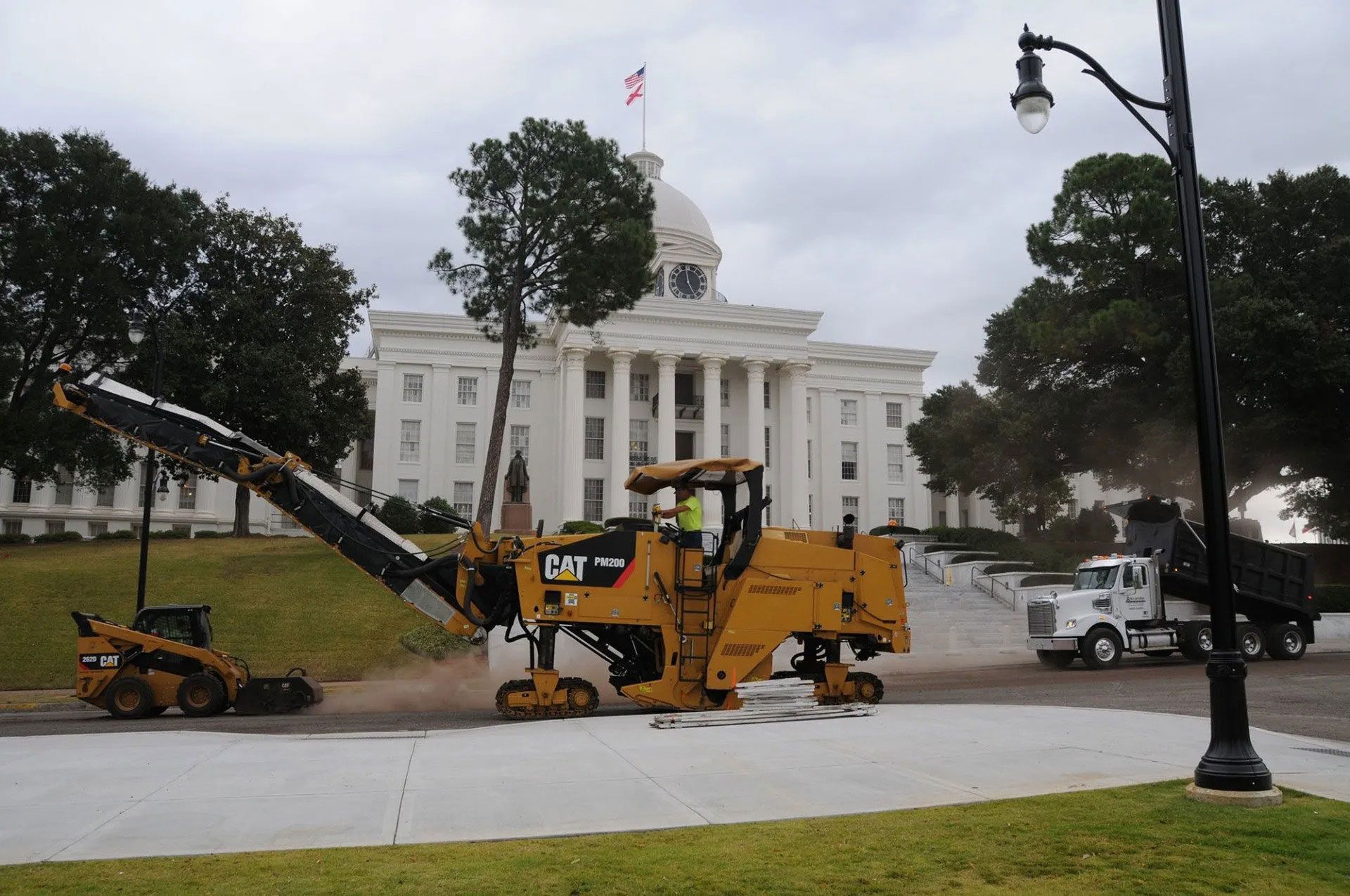 Construction equipment beside a white courthouse on a rainy day
