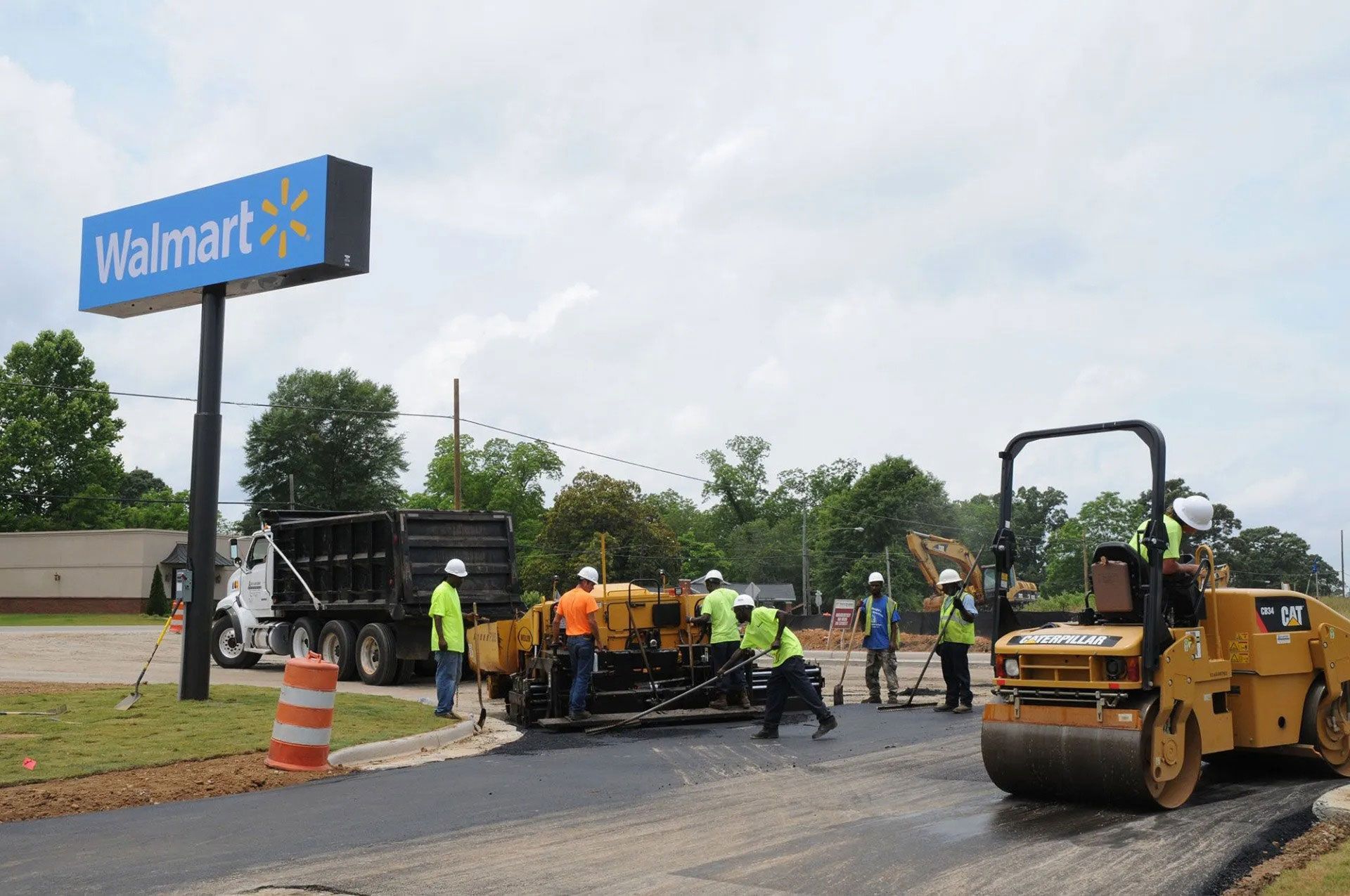 Roadwork crew and heavy equipment repairing pavement near a Walmart sign