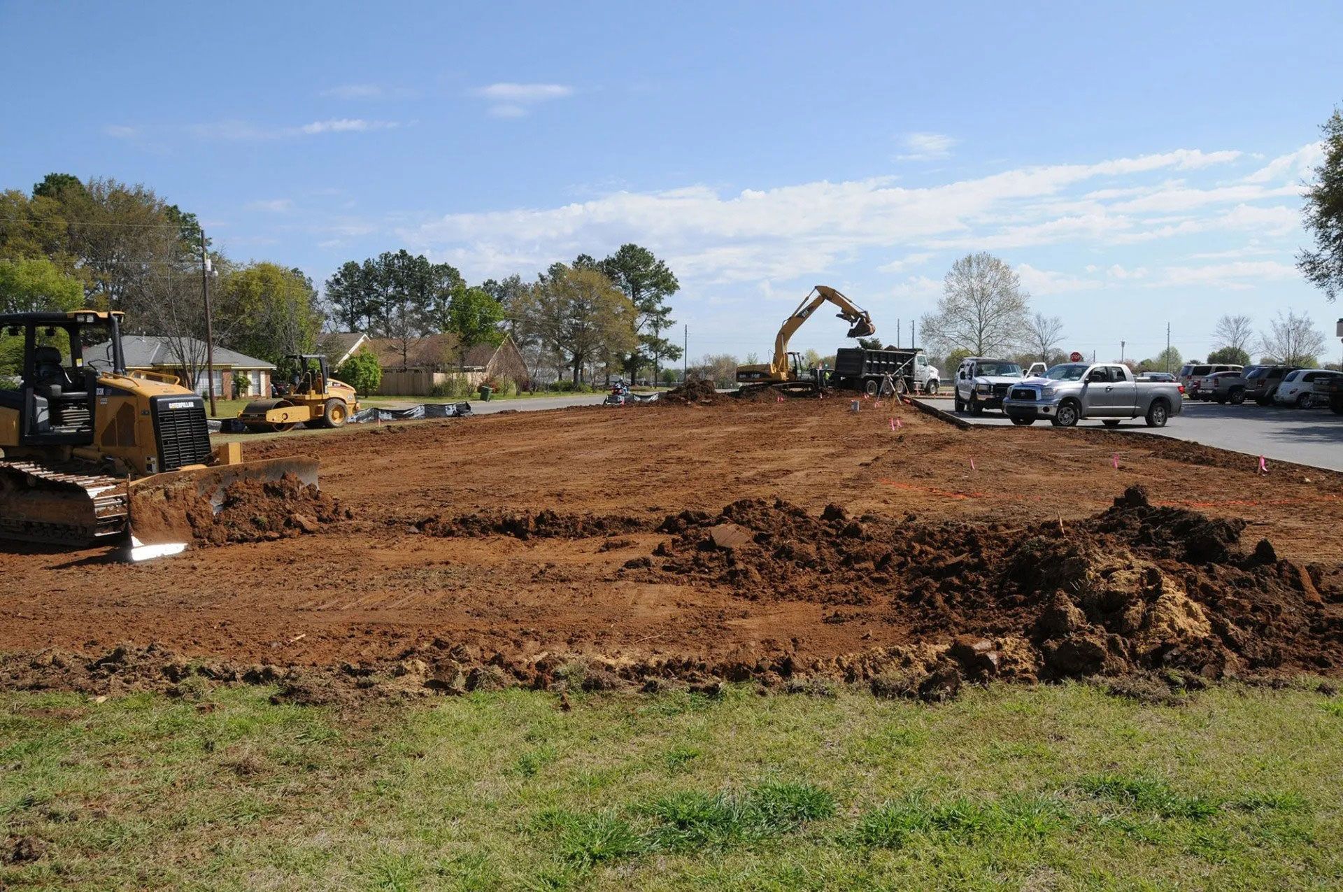 Construction site with excavators and dirt cleared for grading under a blue sky