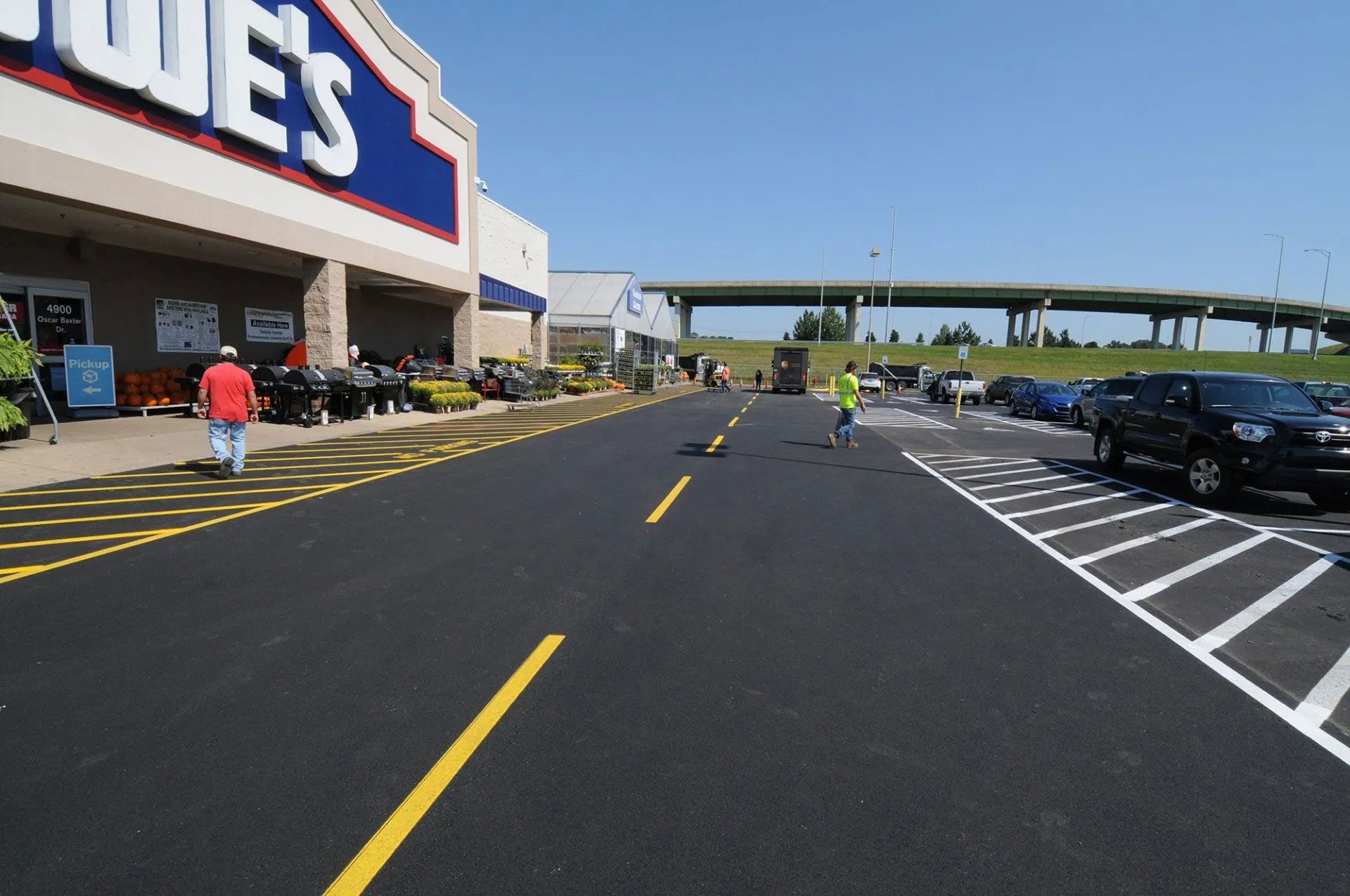 Lowe’s store parking lot with a few shoppers, empty spaces, and a clear sky overhead.