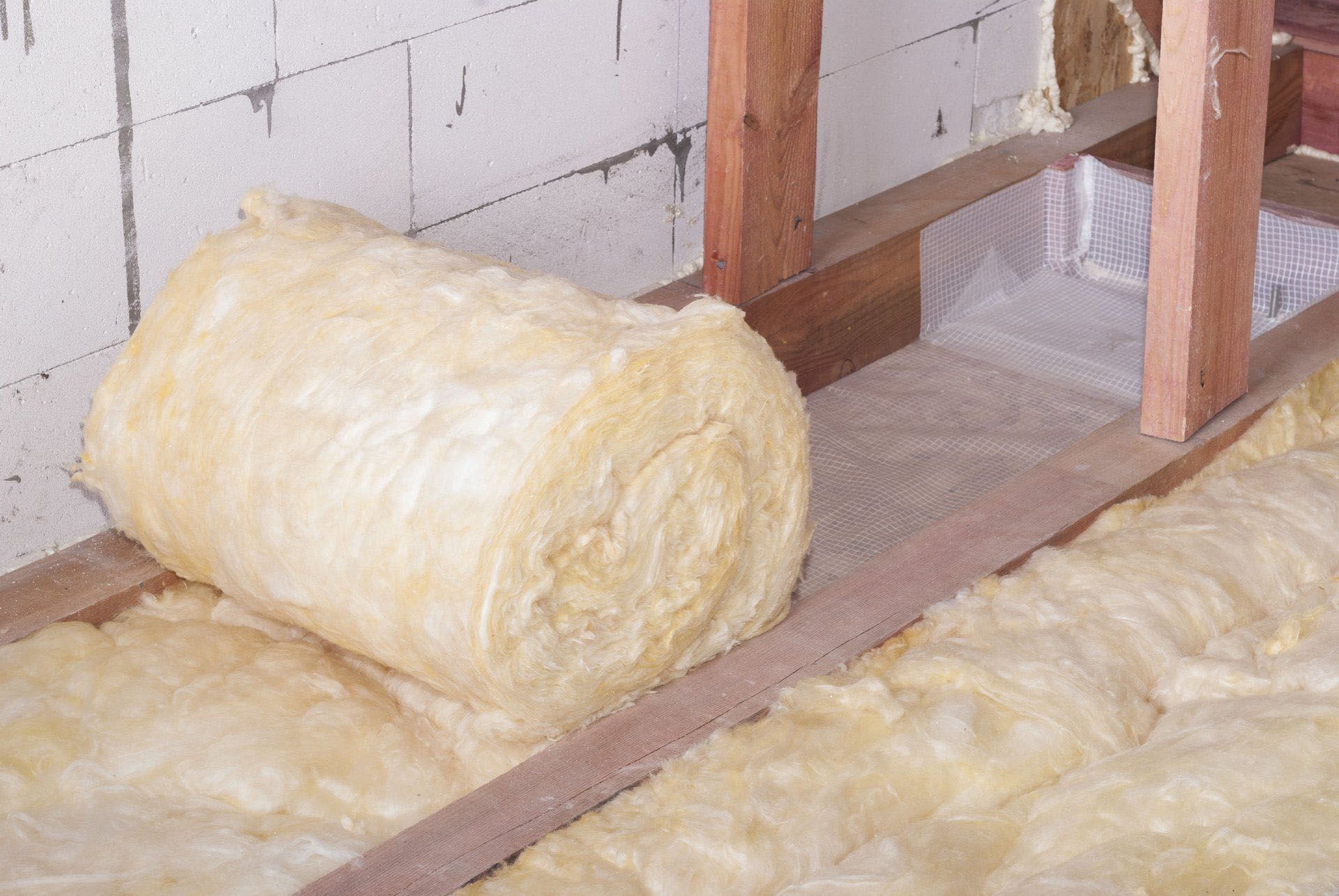 A roll of insulation is sitting on a wooden floor.